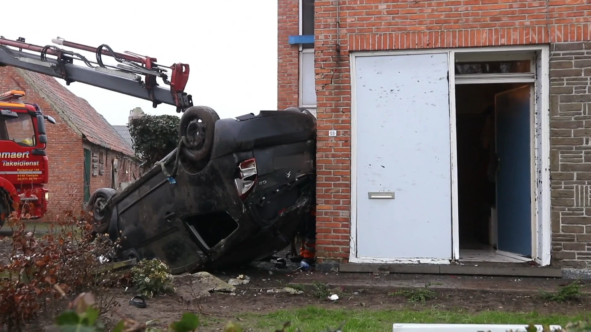 Auto over de kop door voortuin en tegen huisgevel in Lokeren